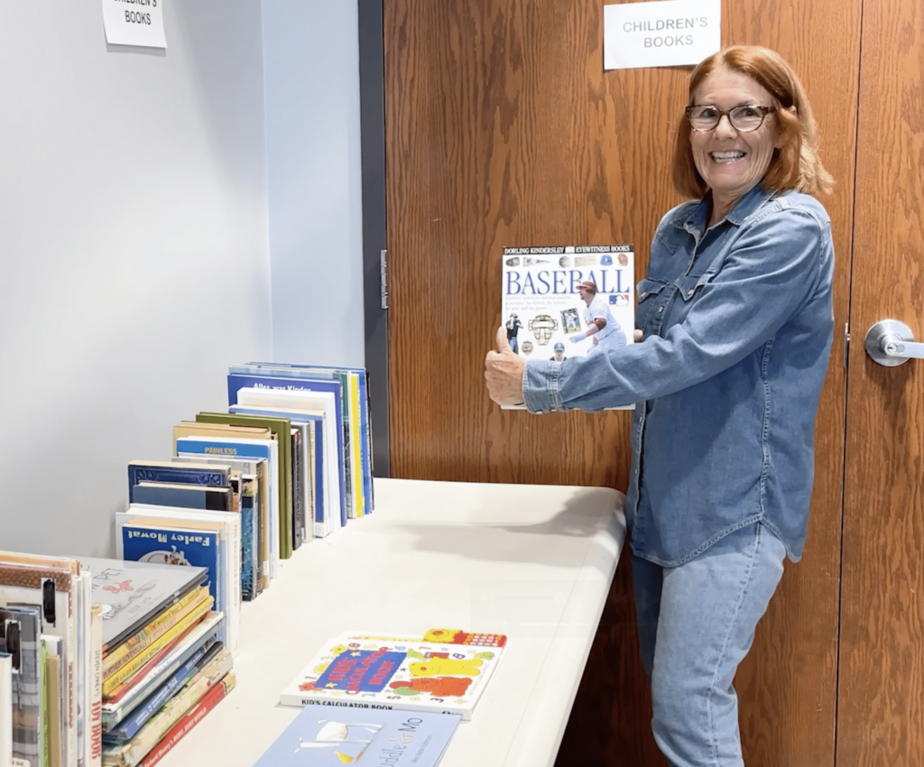 A friend of the library holds up a youth baseball book while preparing for the annual Friend's book sale.