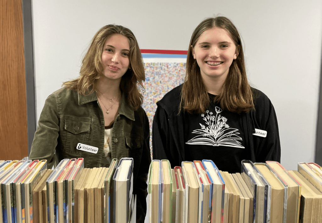 Volunteers smile at the camera while shelf reading.